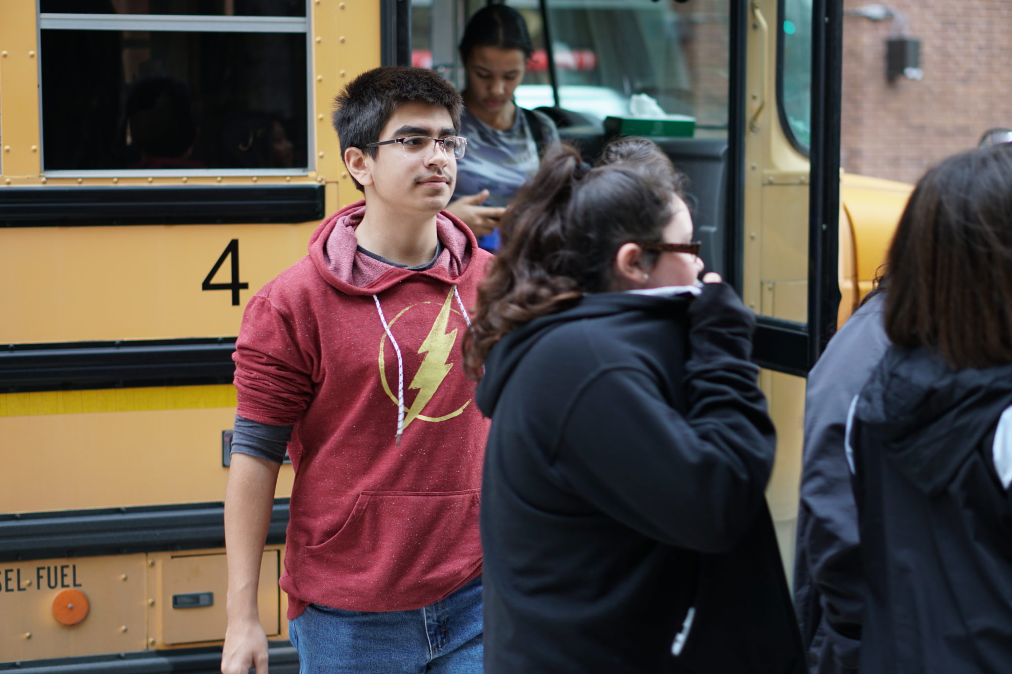red jacket students with glasses getting off the bus